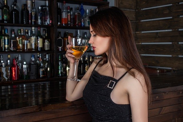 Femme tenant un verre d'alcool à la main droite dans un bar